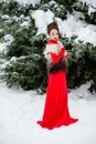 Girl in red dress walking in winter forest