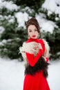 Girl in red dress walking in winter forest