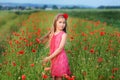 Beautiful girl in red dress walks at poppy field Royalty Free Stock Photo