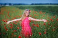 Beautiful girl in red dress walks at poppy field Royalty Free Stock Photo