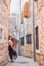 Beautiful Girl with red hair in dress posing in one of city passages with a lot of windows