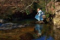 Beautiful girl with red hair reflected in ripples and still water of a rocky pool