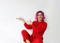 A beautiful girl in a red jumpsuit points with her fingers pointing to the side. Represents your product. Highlighted on Royalty Free Stock Photo