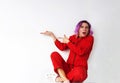 A beautiful girl in a red jumpsuit points with her fingers pointing to the side in surprise. Represents your product Royalty Free Stock Photo