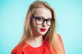 Beautiful girl with red lips and glasses with black frames looking at the camera on a blue background. Health, good vision, ophtha Royalty Free Stock Photo