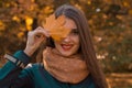 Beautiful girl with red lips in the scarf holds a maple leaf near the eyes and smiles Royalty Free Stock Photo