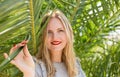 Beautiful girl with red lips smiling and posing in tropical forest. Portrait of tender woman looking out of palm leaf Royalty Free Stock Photo