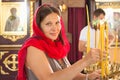 Beautiful girl in a red scarf puts candles in an Orthodox Christian Church