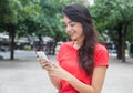 Beautiful girl with red shirt surfing the net with phone Royalty Free Stock Photo