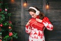Beautiful girl in a red sweater wondering what inside christmas box