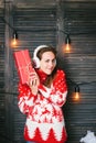 Beautiful girl in a red sweater wondering what inside christmas box.