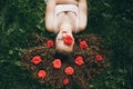 A Beautiful Girl Rest At The Green Grass With Red Roses In Her Hair.