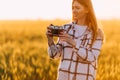 Beautiful girl with retro camera, on a Golden wheat field against the background of a Sunny sunset Royalty Free Stock Photo
