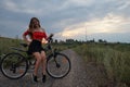 Beautiful girl riding bike at fields at sunset