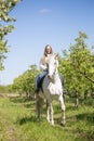 Beautiful girl riding a horse on a white horse in the garden Royalty Free Stock Photo