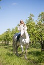 Beautiful girl riding a horse on a white horse in the garden Royalty Free Stock Photo