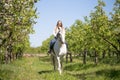 Beautiful girl riding a horse on a white horse in the garden Royalty Free Stock Photo