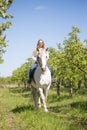 Beautiful girl riding a horse on a white horse in the garden Royalty Free Stock Photo