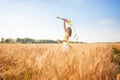 A beautiful girl runs with a kite on the field. A beautiful young woman with a flying multicolored kite over a clear Royalty Free Stock Photo