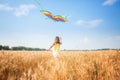 A beautiful girl runs with a kite on the field. A beautiful young woman with a flying multicolored kite over a clear Royalty Free Stock Photo