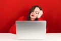 Beautiful girl is sad at the computer on a red background Royalty Free Stock Photo