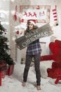 Beautiful girl in Santa Claus hat showing wooden signboard with