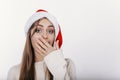 Beautiful girl in santa hat covering her mouth by handYoung european woman in santa hat covering her mouth by hand Royalty Free Stock Photo