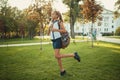 A beautiful girl of school age is standing by a tree and holding a tablet. Schoolgirl wearing a skirt and a shirt with shoes