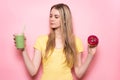 Beautiful girl is selecting between healthy green gluten-free organic smoothie and unhealthy food. Nutrition choice concept. Royalty Free Stock Photo