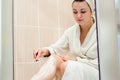 Beautiful girl shaving her legs using a razor while taking shower in bathroom Royalty Free Stock Photo