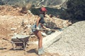 Beautiful girl in the shorts, t-shirt and in the red peaked cap raising up a shovel with gravel Royalty Free Stock Photo