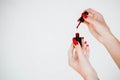 Beautiful girl showing red manicure nails. red nail polish bottle on white background. Stylish trendy female manicure. Royalty Free Stock Photo