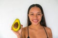 Beautiful girl showing white teeth, perfect facial skin, holding an avocado