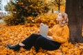 A beautiful girl sits in an autumn park with a laptop. The student studies on the street. The girl closed her eyes and Royalty Free Stock Photo