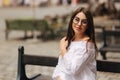 Beautiful girl sits on benth in centre of city. She relaxes and waits for her husband Royalty Free Stock Photo