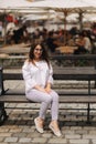 Beautiful girl sits on benth in centre of city. She relaxes and waits for her husband Royalty Free Stock Photo