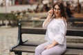 Beautiful girl sits on benth in centre of city. She relaxes and waits for her husband Royalty Free Stock Photo