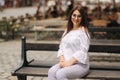 Beautiful girl sits on benth in centre of city. She relaxes and waits for her husband Royalty Free Stock Photo