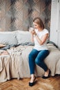 Beautiful girl sits on her bed, reads an interesting book, enjoys of her life and smiles Royalty Free Stock Photo