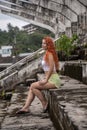 A beautiful girl sits in the stands of an abandoned stadium. It's a nasty day.