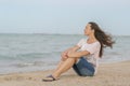 Beautiful girl sitting on the beach. Middle aged woman resting at beach near the sea. young, beautiful woman with long Royalty Free Stock Photo