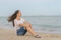 Beautiful girl sitting on the beach. Middle aged woman resting at beach near the sea. young, beautiful woman with long flowing Royalty Free Stock Photo