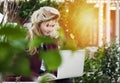 Beautiful girl is sitting on a bench with a laptop in her hands on a fresh street with the city. A concept work in pleasure,