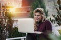 Beautiful girl is sitting on a bench with a laptop in her hands on a fresh street with the city. A concept work in pleasure,