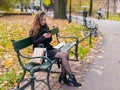 Beautiful girl sitting on a bench, woman with your phone writes a message on social networks, sunny autumn day in the park, woman Royalty Free Stock Photo