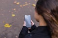 Beautiful girl sitting on a bench, woman with your phone writes a message on social networks, sunny autumn day in the park, woman Royalty Free Stock Photo