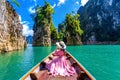 Beautiful girl sitting on the boat and looking to mountains in Ratchaprapha Dam. Royalty Free Stock Photo