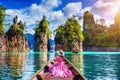 Beautiful girl sitting on the boat and looking to mountains in Ratchaprapha Dam at Khao Sok National Park, Surat Thani Province Royalty Free Stock Photo