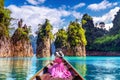 Beautiful girl sitting on the boat and looking to mountains in Ratchaprapha Dam at Khao Sok National Park, Surat Thani Province