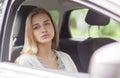 A beautiful girl is sitting in the car and with sadness in her eyes, looks out the open window. Royalty Free Stock Photo